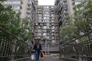 A man walks on a pedestrian bridge near residential buildings in Beijing, China Oct. 17, 2024.