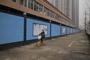 A woman cycles past the closed Huanan Seafood wholesale market in Wuhan, China's central Hubei province on Jan. 23, 2021, one year after the city went into lockdown to curb the spread of the Covid-19 coronavirus.