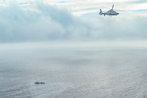 An aircraft identified by the Philippine Coast Guard as Chinese Navy helicopter (L) flies near the Bureau of Fisheries and Aquatic Resources (BFAR) plane during an aerial reconnaissance flight at Scarborough Shoal in the South China Sea on Feb. 18, 2025.